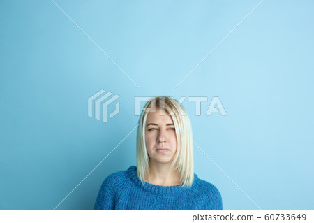 Portrait of young caucasian woman looks happy, dreamful on blue background 60733649