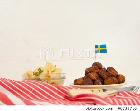 Traditional swedish meatballs (kottbullar) with cauliflower and green peas in the white plate. Swedish flags. Swedish national food concept. Background photo with place for text 60733710