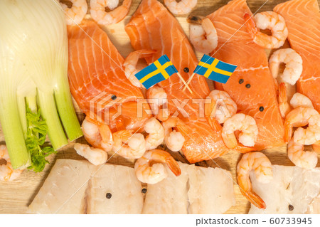 Salmon, cod, shrimps and black pepper on a wooden board. Swedish flags. National food Salmon, cod, shrimps and black pepper on a wooden board. Swedish flags. National food 60733945