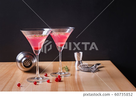 Martini glasses with cranberry cocktail and barmen tools on the wooden table. 60735852