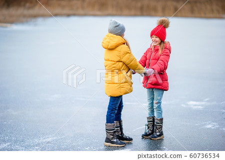 Adorable little girls skating on the ice-rink Adorable little girls skating on the ice-rink 60736534