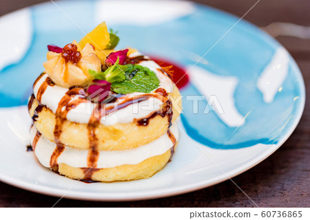 Cottage cheese pancakes or syrniki with cream, fruit jam and flower decoration Cottage cheese pancakes or syrniki with cream, fruit jam and flower decoration 60736865