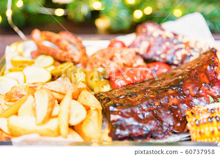 Dish of mixed meats. Grilled ribs, chicken and sausages served with baked potato Dish of mixed meats. Grilled ribs, chicken and sausages served with baked potato 60737958
