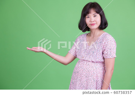Portrait of beautiful Asian pregnant woman showing something Portrait of beautiful Asian pregnant woman showing something 60738357