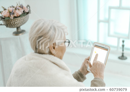 Old Grey-haired Woman Having A Rest At Home With A Tablet in Her Hand. Old Grey-haired Woman Having A Rest At Home With A Tablet in Her Hand. 60739079