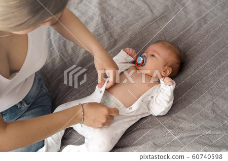 Mother with her newborn son laying on the bed in the rays of sunlight  60740598