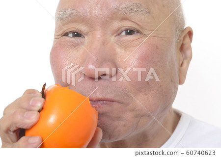 Smiling senior eating persimmon Smiling senior eating persimmon 60740623