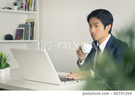 Asian Businessman Drink Coffee in Break Time with Tree Foreground in Vintage Tone Asian Businessman Drink Coffee in Break Time with Tree Foreground in Vintage Tone 60745264