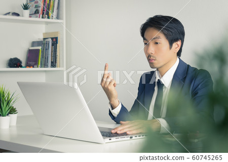 Asian Businessman Angry Partner and Show Middle Finger in front of Laptop in Vintage Tone Asian Businessman Angry Partner and Show Middle Finger in front of Laptop in Vintage Tone 60745265