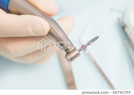 During the operation, the dentist holds implantation tools with a titanium implant 60745705