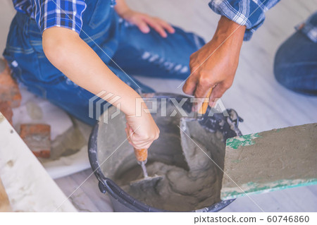 Senior contractor is teaching a boy kid to mix 60746860