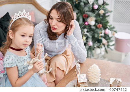 Cheerful mom embraces her cute baby daughter . Parent and little child having fun near Christmas tree indoors. Loving family Merry Christmas and Happy New Year Cheerful mom embraces her cute baby daughter . Parent and little child having fun near Christmas tree indoors. Loving family Merry Christmas and Happy New Year 60747332