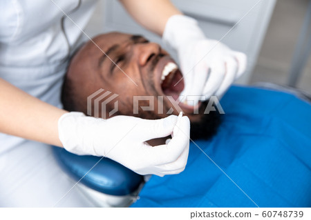 Young african-american man visiting dentist's office, looks scared Young african-american man visiting dentist's office, looks scared 60748739