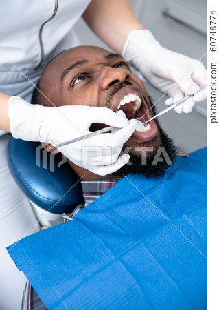 Young african-american man visiting dentist's office, looks scared 60748774