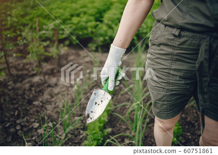 Beautiful woman works in a garden near the house 60751861