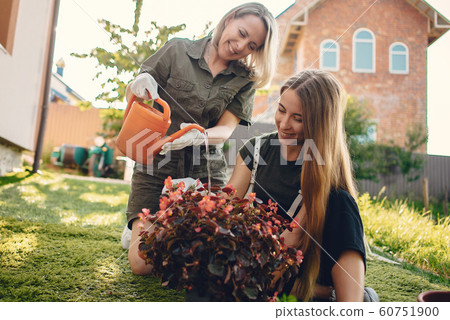 Mother with a daughter works in a garden near the house Mother with a daughter works in a garden near the house 60751900