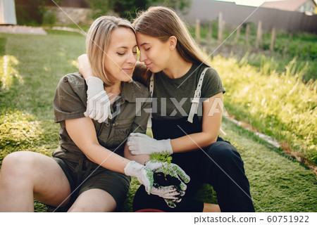 Mother with a daughter works in a garden near the house Mother with a daughter works in a garden near the house 60751922