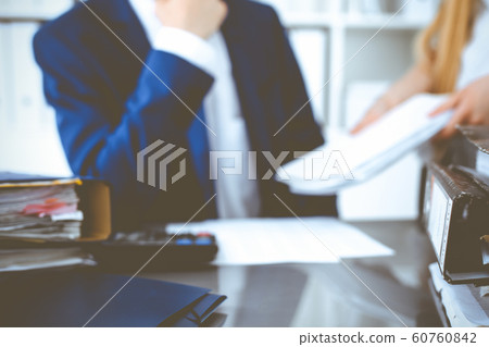 Binders with papers waiting to be processed with businessman or bookkeeper back in blur. Accounting planning budget. Audit, insurance and business concept Binders with papers waiting to be processed with businessman or bookkeeper back in blur. Accounting planning budget. Audit, insurance and business concept 60760842