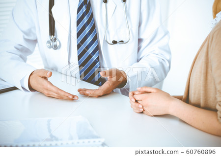 Doctor and patient woman discussing something at the desk in hospital office. Concepts of medical ethics and helping people in medicine Doctor and patient woman discussing something at the desk in hospital office. Concepts of medical ethics and helping people in medicine 60760896