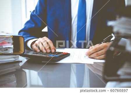 Bookkeeper or financial inspector hands making report, calculating or checking balance. Internal Revenue Service inspector man checking financial document. Business, tax and audit concepts Bookkeeper or financial inspector hands making report, calculating or checking balance. Internal Revenue Service inspector man checking financial document. Business, tax and audit concepts 60760897