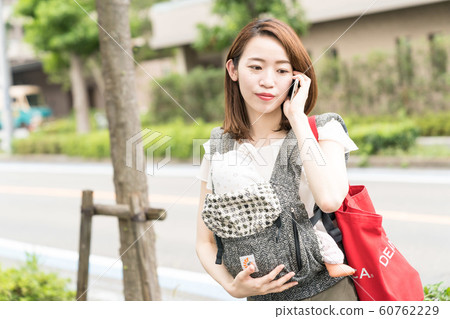 A woman holding a baby and calling 60762229