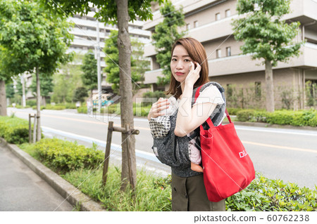 A woman holding a baby and calling 60762238