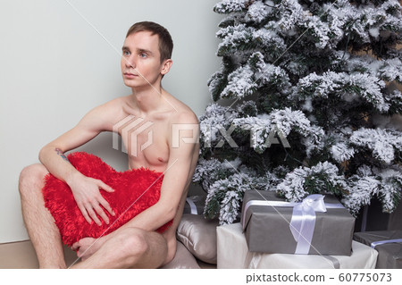 Young man with big present sitting on floor near 60775073