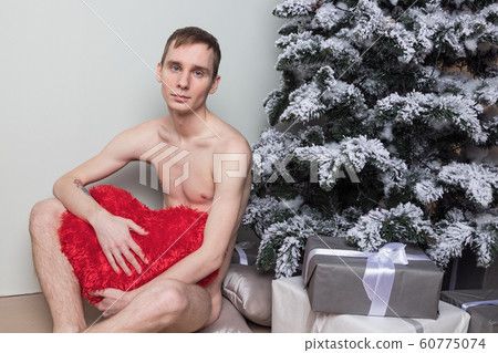 Young man with big present sitting on floor near Young man with big present sitting on floor near 60775074