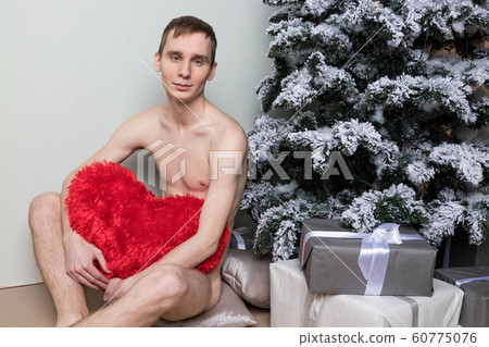 Young man with big present sitting on floor near Young man with big present sitting on floor near 60775076