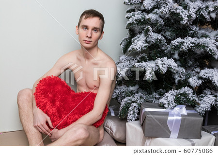 Young man with big present sitting on floor near Young man with big present sitting on floor near 60775086