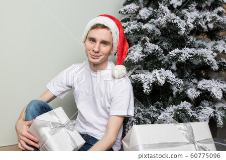 Young man with big present sitting on floor near Young man with big present sitting on floor near 60775096