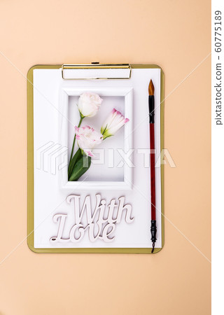 Clipboard with eustoma flower and white frame on beige paper background, flat lay. Post card mockup 60775189