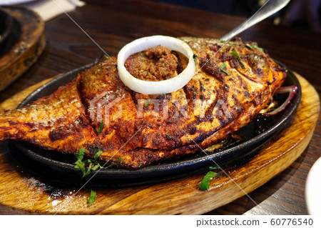 Whole fish Tandoori on a sizzling plate.   60776540