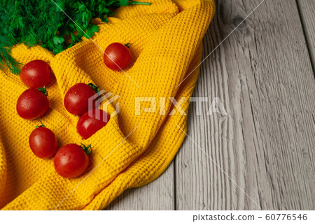 Cherry tomatoes with greens on a yellow towel Cherry tomatoes with greens on a yellow towel 60776546