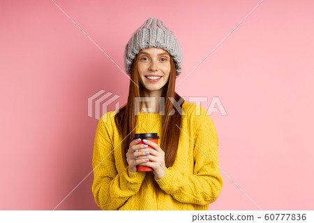 Redhead woman holding disposable cup of coffee 60777836