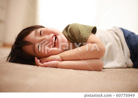 一個男孩躺著看電視 60778949