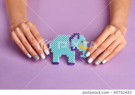 Blue toy elephant and female manicure on a violet Blue toy elephant and female manicure on a violet 60782483