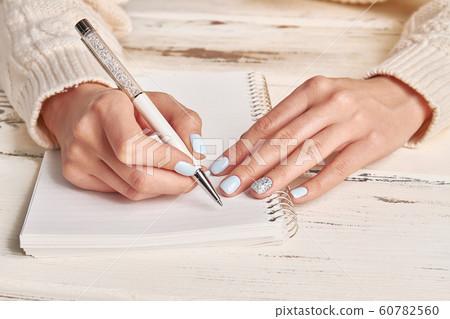 Woman writing in spiral notepad placed on wooden Woman writing in spiral notepad placed on wooden 60782560