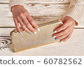 Beautiful golden clutch in women's hands. 60782562