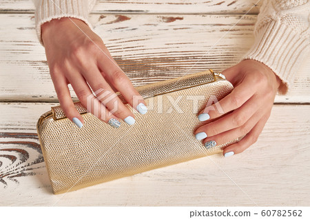 Beautiful golden clutch in women's hands. 60782562