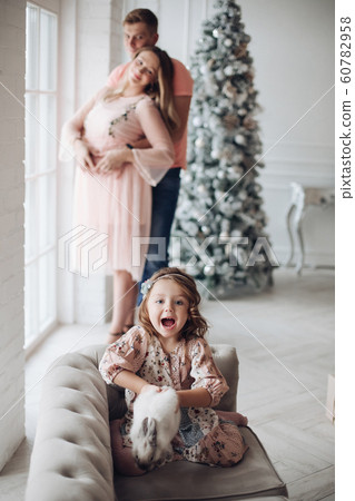 Excited girl with bunny against hugging parents. Excited girl with bunny against hugging parents. 60782958