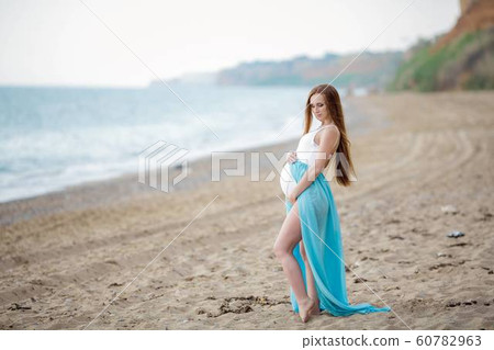 Pregnant adult woman on the shore of a warm summer sea 60782963