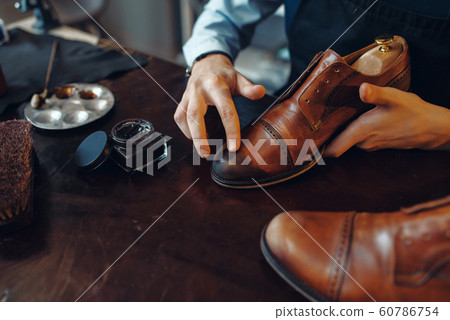 Shoemaker applies shoe polish, footwear repair Shoemaker applies shoe polish, footwear repair 60786754