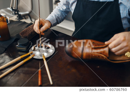 Bootmaker with brush tints shoes, footwear repair 60786760