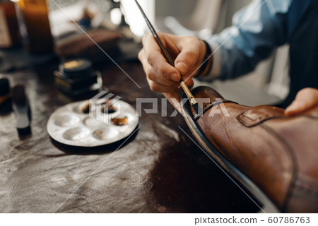 Shoemaker with brush tints shoes, footwear repair 60786763