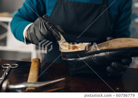 Shoemaker smears glue to the shoe, footwear repair Shoemaker smears glue to the shoe, footwear repair 60786779