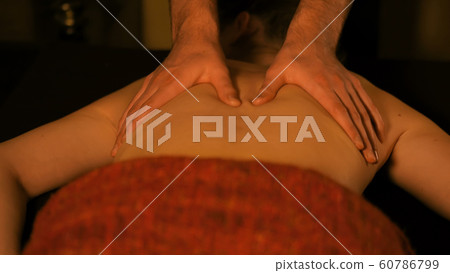 Masseur doing back massage for female client in spa center Masseur doing back massage for female client in spa center 60786799