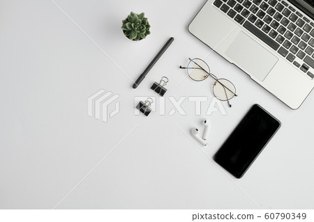 Cordless earphones, eyewear, pen, clips, mobile gadget, green plant and laptop 60790349