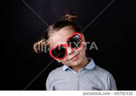 Cute girl in sunglasses with heartshaped lens standing in front of camera 60792332