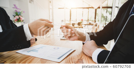 Close-up view of business people giving a contact 60792708